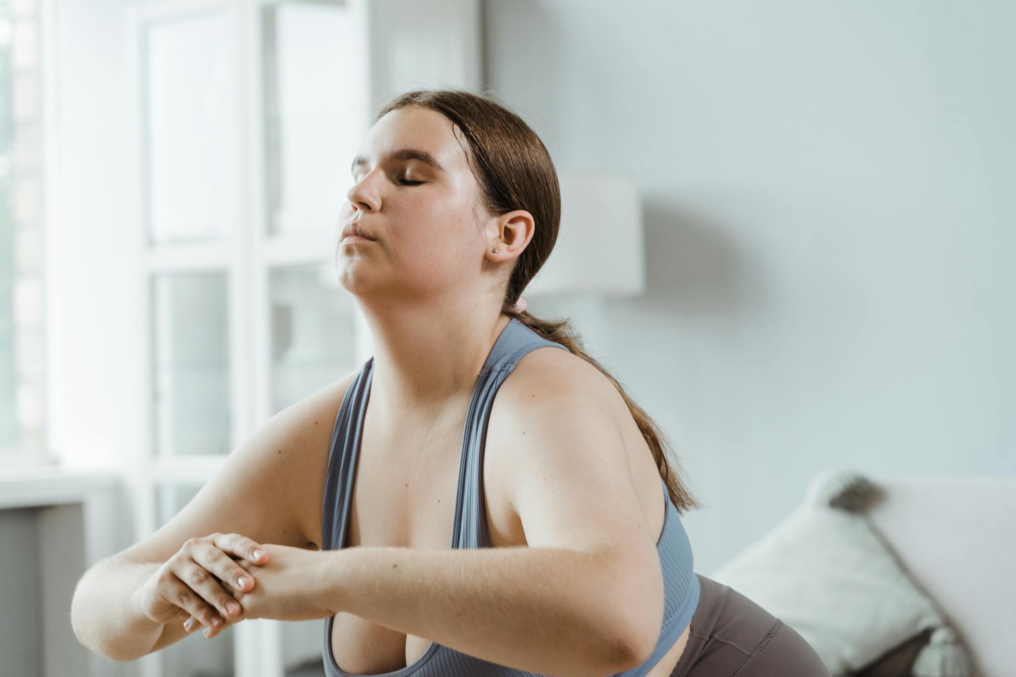 Home A plus size woman practicing yoga indoors with focus on wellness and relaxation.