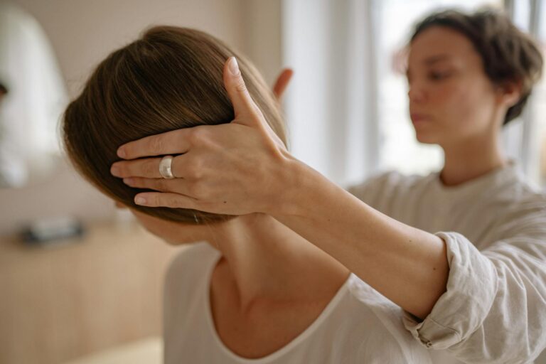 Woman undergoing therapeutic touch therapy session indoors with focused therapist.